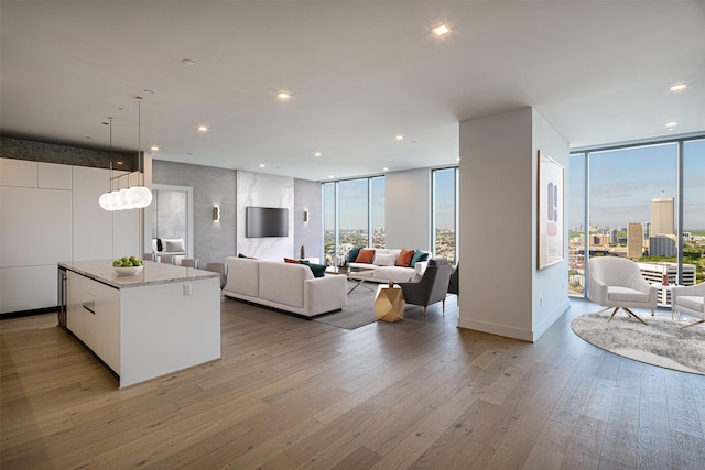 interior space featuring white cabinets, a wall of windows, hanging light fixtures, a center island, and light hardwood / wood-style floors