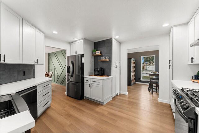 kitchen featuring backsplash, black appliances, and white cabinets