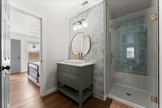 bathroom with vanity, hardwood / wood-style floors, a textured ceiling, and walk in shower