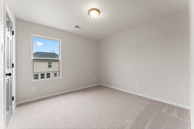 empty room featuring light colored carpet and a textured ceiling