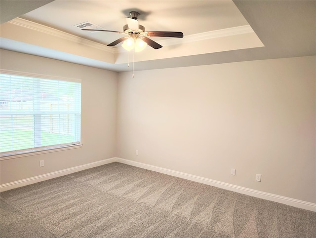 carpeted empty room featuring a raised ceiling, ornamental molding, and ceiling fan