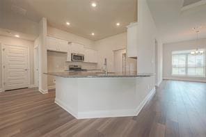 kitchen with sink, dark hardwood / wood-style floors, kitchen peninsula, a notable chandelier, and white cabinets