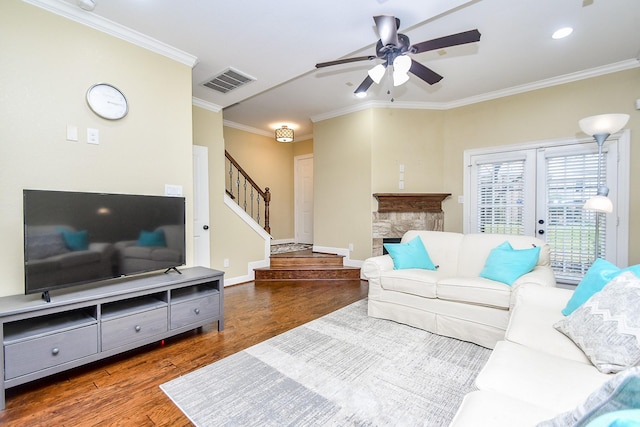 living room with ornamental molding, dark wood-type flooring, ceiling fan, and a fireplace