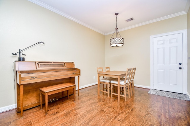 dining area with crown molding and light hardwood / wood-style floors