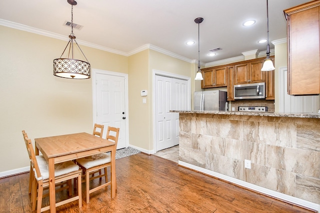 kitchen featuring stainless steel appliances, light stone countertops, hanging light fixtures, and light hardwood / wood-style floors