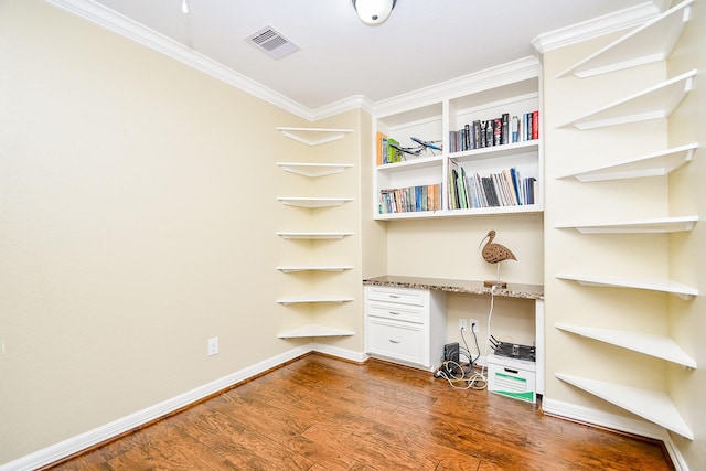 unfurnished office with dark hardwood / wood-style flooring, crown molding, and built in desk