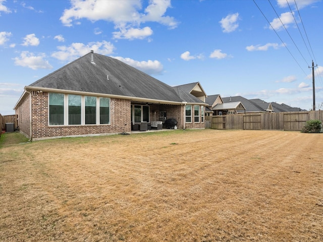 rear view of property with cooling unit and a yard