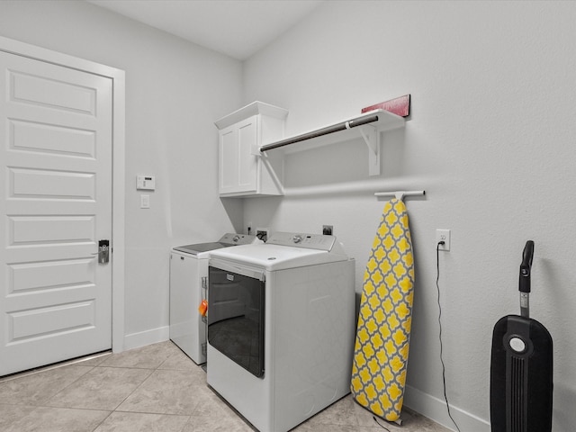 laundry area with cabinets, light tile patterned floors, and washing machine and clothes dryer