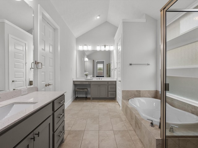 bathroom featuring lofted ceiling, vanity, tile patterned flooring, and tiled bath