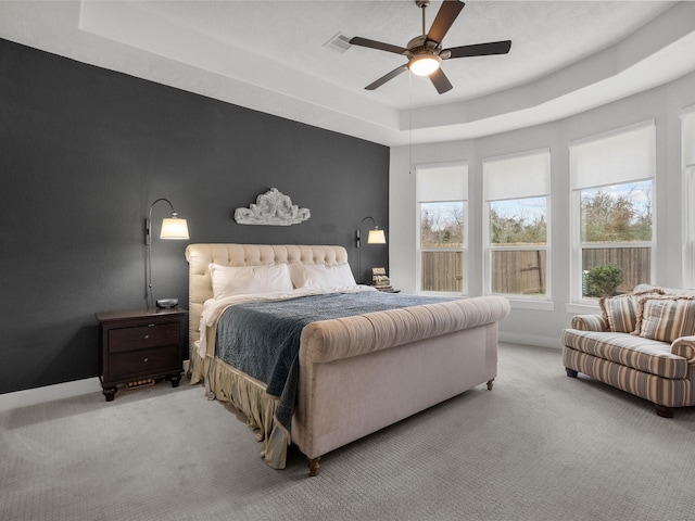 bedroom featuring light carpet, multiple windows, and a raised ceiling