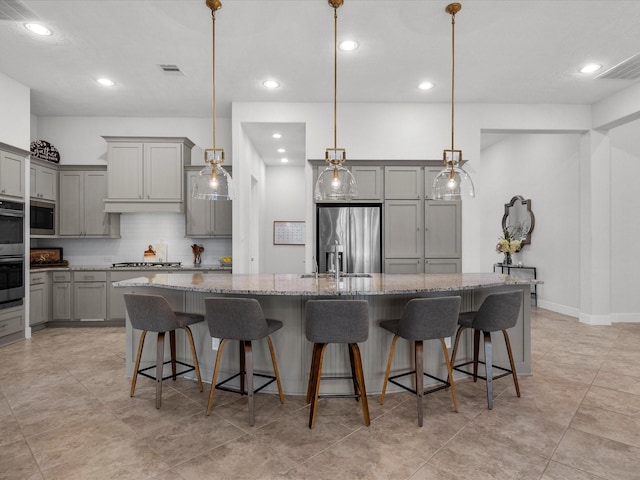 kitchen with pendant lighting, a breakfast bar, stainless steel appliances, a spacious island, and light stone countertops