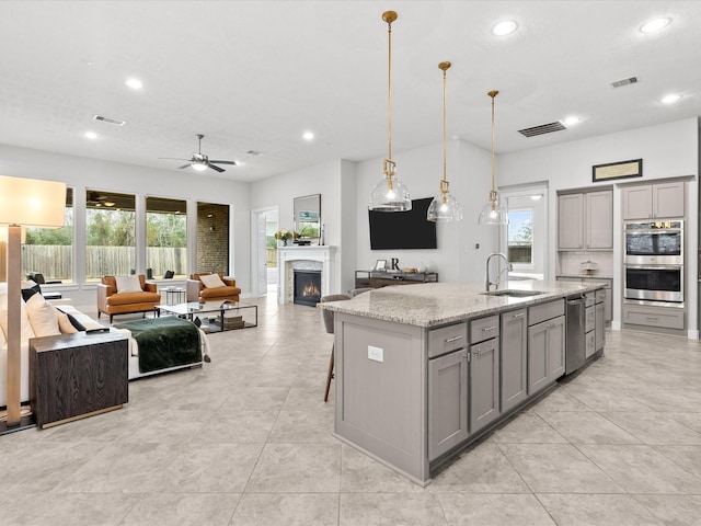 kitchen featuring a center island with sink, hanging light fixtures, and gray cabinetry