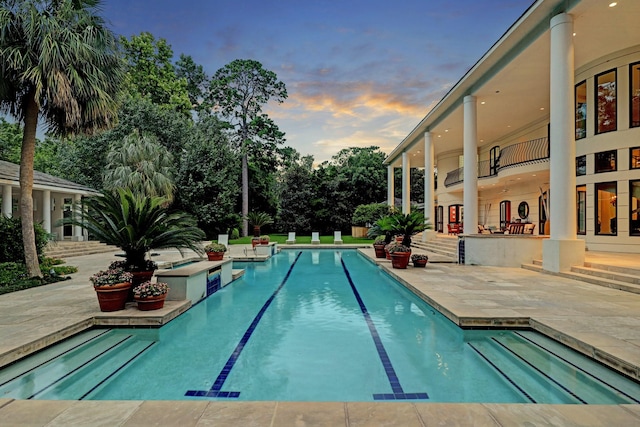 pool at dusk featuring a patio area