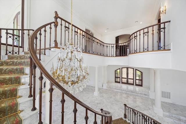 stairway featuring ornate columns, crown molding, a high ceiling, and a chandelier