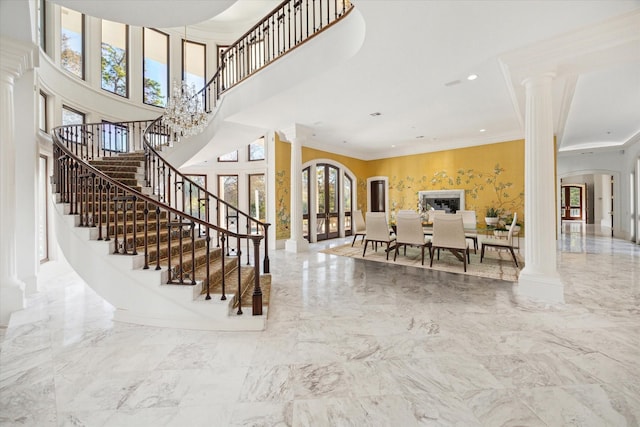 interior space featuring ornate columns, ornamental molding, and a towering ceiling