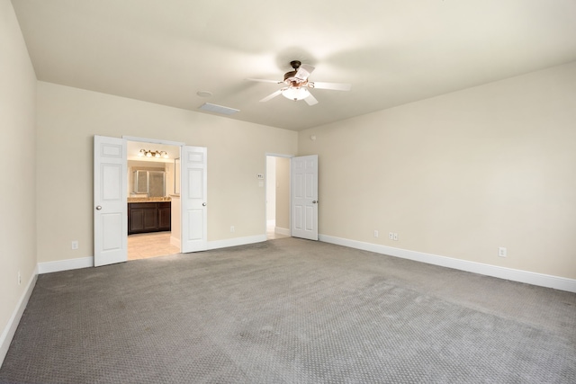 unfurnished bedroom with ceiling fan, light colored carpet, and ensuite bath