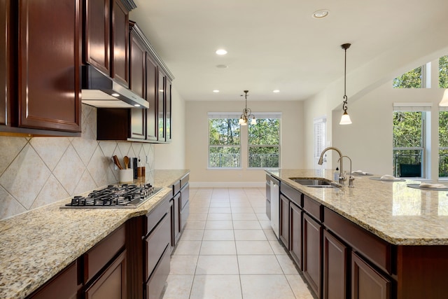 kitchen featuring appliances with stainless steel finishes, pendant lighting, sink, backsplash, and light stone counters