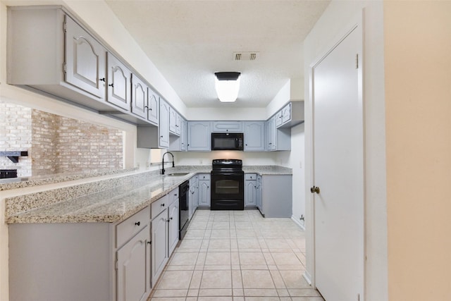 kitchen with light tile patterned flooring, sink, gray cabinetry, light stone countertops, and black appliances