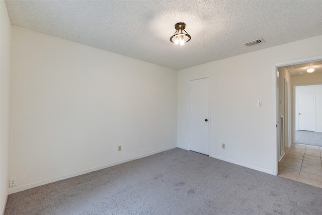 spare room with light colored carpet and a textured ceiling