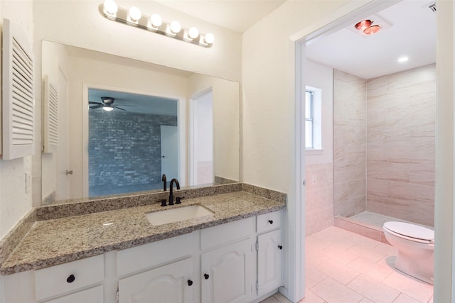 bathroom featuring tile patterned floors, vanity, toilet, and a tile shower