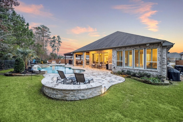 back house at dusk with a fenced in pool, a fire pit, a patio area, and a lawn