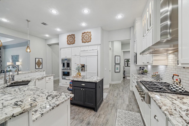 kitchen with sink, stainless steel appliances, a center island, white cabinets, and wall chimney exhaust hood