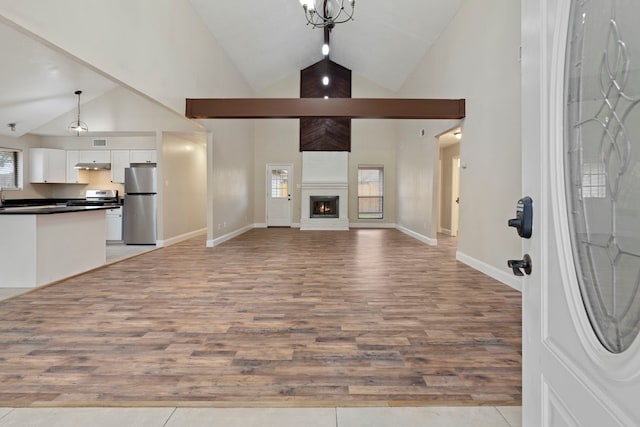 unfurnished living room featuring high vaulted ceiling, a fireplace, and light wood-type flooring