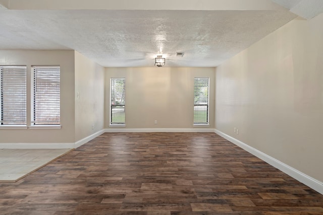 spare room featuring dark wood-type flooring and a textured ceiling