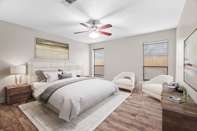 bedroom with hardwood / wood-style flooring, ceiling fan, and a textured ceiling