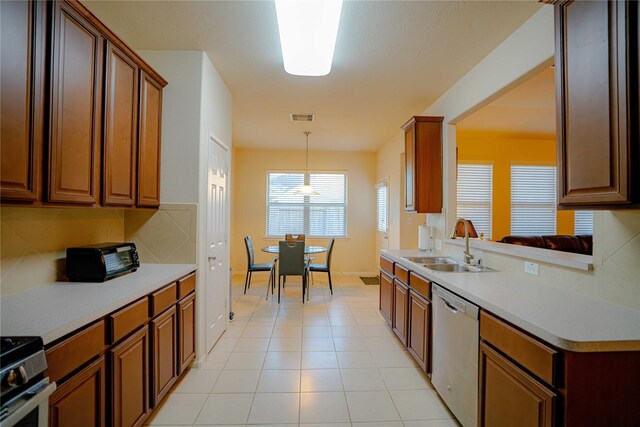 15830 Mesenbrink Ln, Houston, TX 77049 - kitchen with appliances with stainless steel finishes, sink, backsplash, hanging light fixtures, and light tile patterned floors