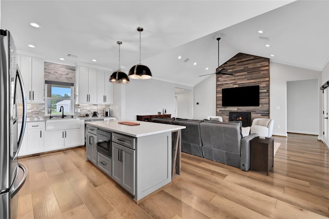 kitchen with sink, white cabinetry, a kitchen island, pendant lighting, and stainless steel appliances