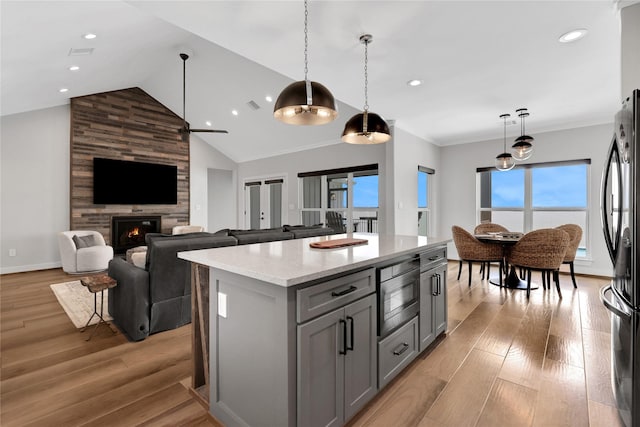 kitchen with a center island, black refrigerator, stainless steel microwave, gray cabinets, and pendant lighting