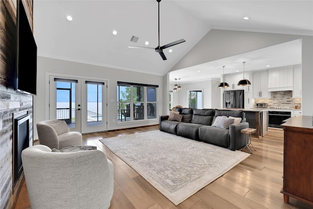 living room with high vaulted ceiling, crown molding, light hardwood / wood-style floors, and french doors