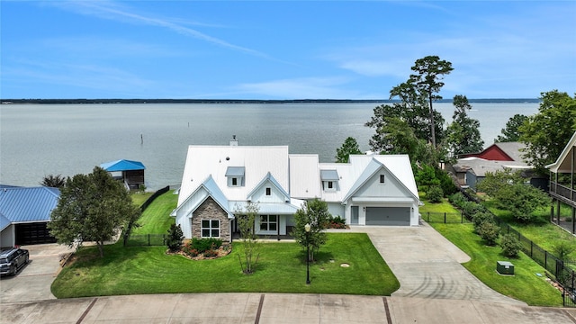 view of front of home with a garage, a water view, and a front yard