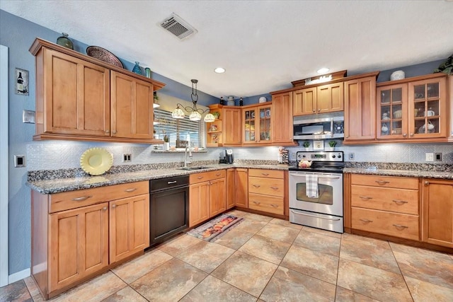 kitchen featuring sink, light stone counters, hanging light fixtures, appliances with stainless steel finishes, and decorative backsplash