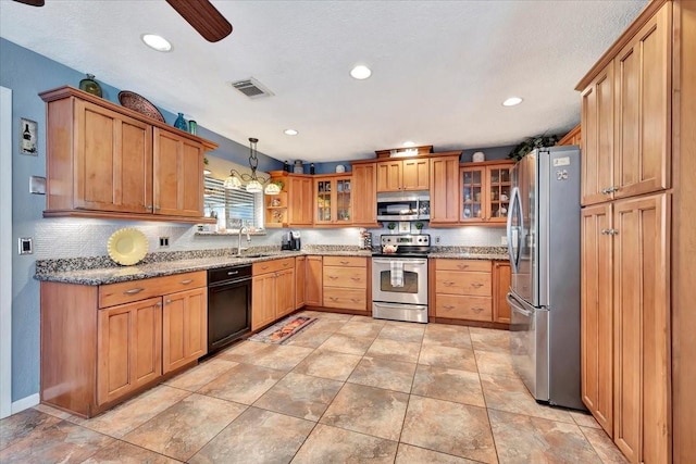 kitchen featuring stainless steel appliances, light stone countertops, hanging light fixtures, and sink