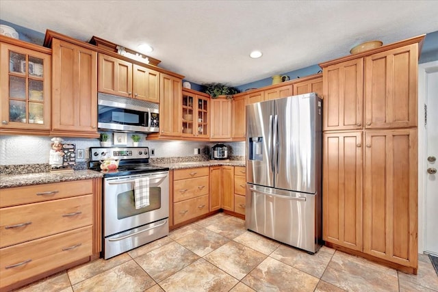 kitchen featuring stainless steel appliances, light stone countertops, and decorative backsplash