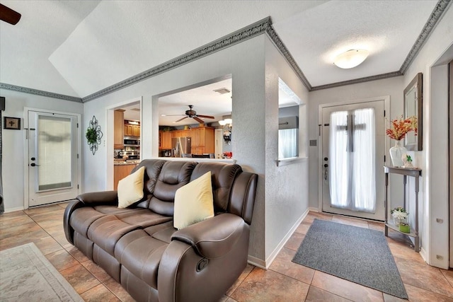 foyer featuring ornamental molding, vaulted ceiling, light tile patterned floors, and a textured ceiling