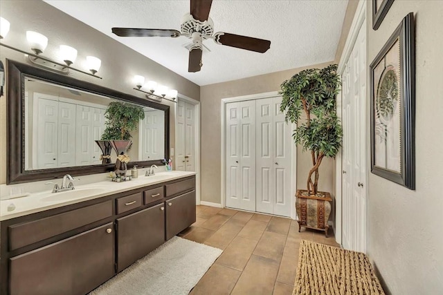 bathroom with ceiling fan, vanity, and a textured ceiling