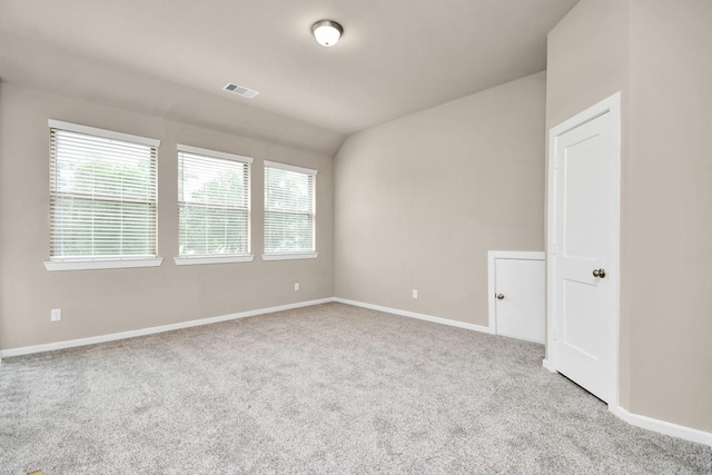 carpeted empty room with vaulted ceiling