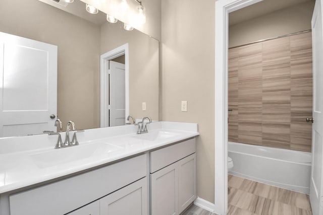 full bathroom with vanity, tiled shower / bath, and toilet