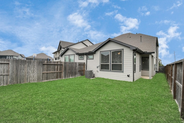 rear view of house with central AC unit and a yard