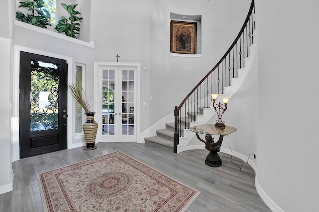 foyer entrance featuring french doors, a towering ceiling, and hardwood / wood-style flooring