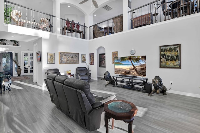 living area featuring visible vents, baseboards, a ceiling fan, and wood finished floors