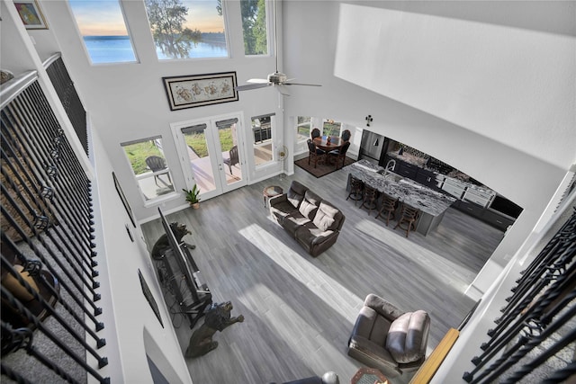 living room featuring hardwood / wood-style flooring, a high ceiling, ceiling fan, and french doors