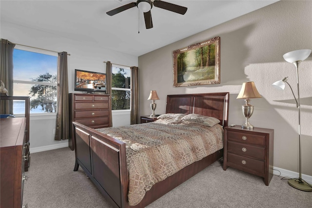 bedroom featuring light carpet, a ceiling fan, and baseboards