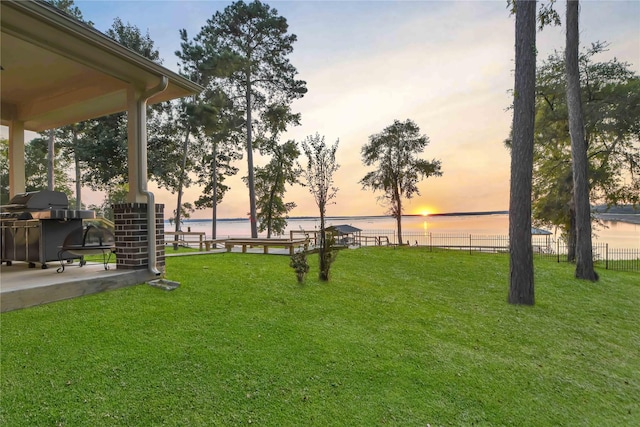 yard at dusk with fence and a water view