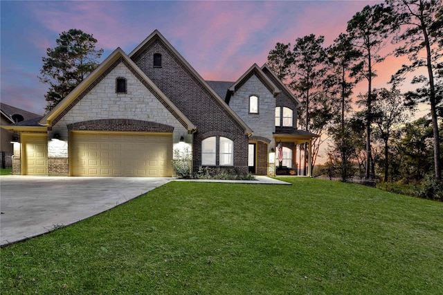 french country inspired facade featuring a yard, brick siding, concrete driveway, and an attached garage