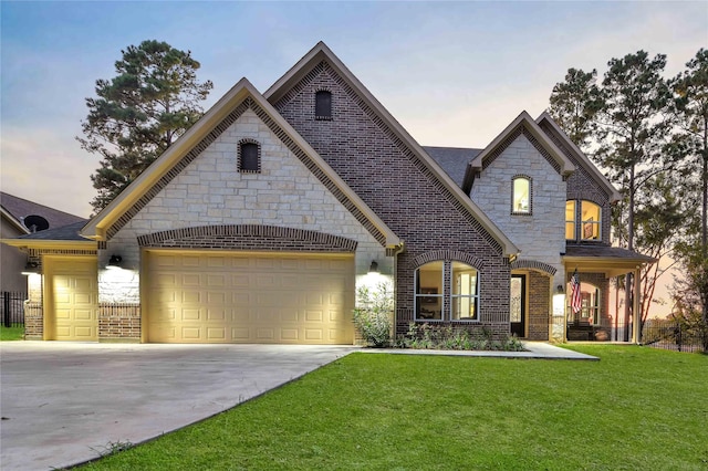 french country inspired facade with a yard, brick siding, a garage, and driveway