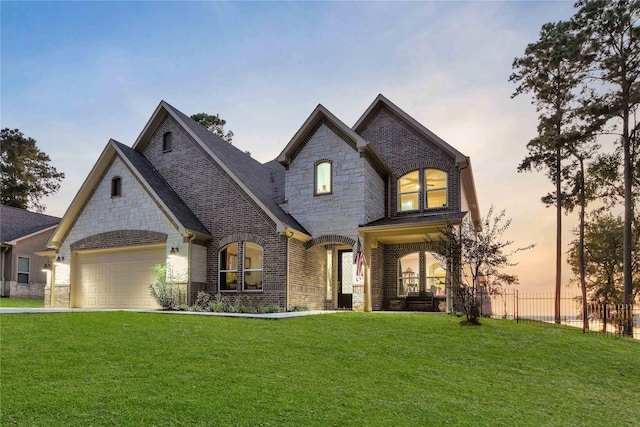 french country home featuring a garage and a lawn